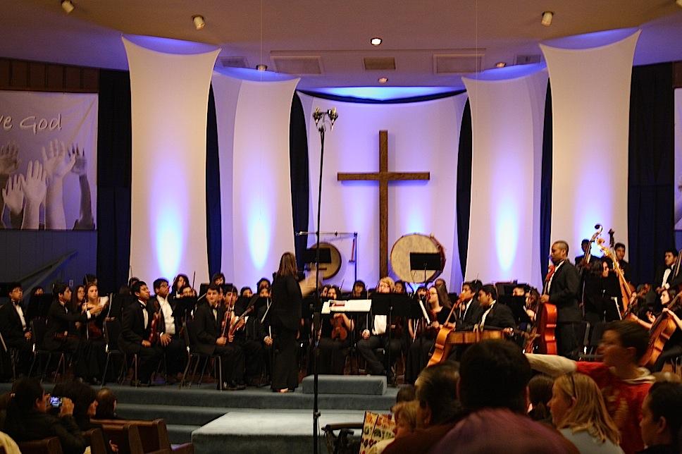 The orchestra plays a song on stage.