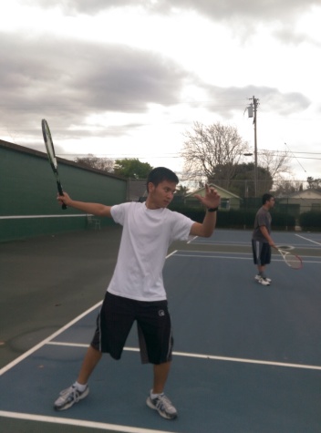 During practice, Jared Devra shows us his serving position and David Zhong is attentive to his match. 